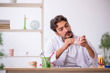 Klinikte çalışan genç erkek dişçi.