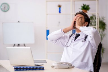 Klinikte çalışan genç erkek doktor.