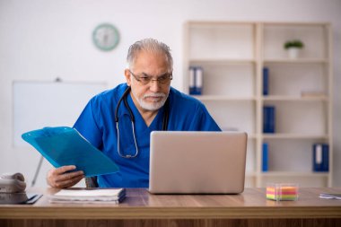 Klinikte çalışan yaşlı erkek doktor.