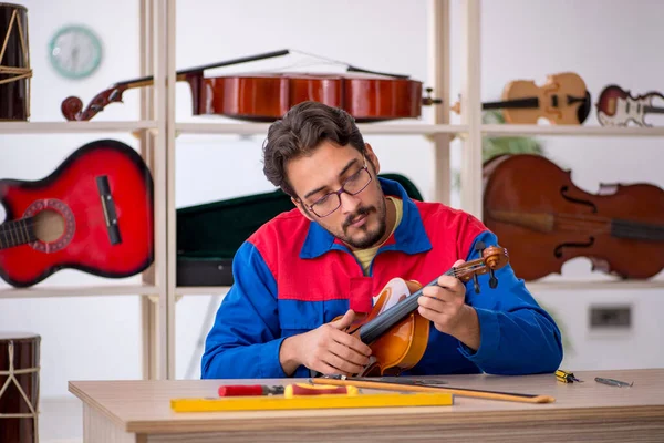 Young man repairing musical instruments at workshop — Stock Photo, Image