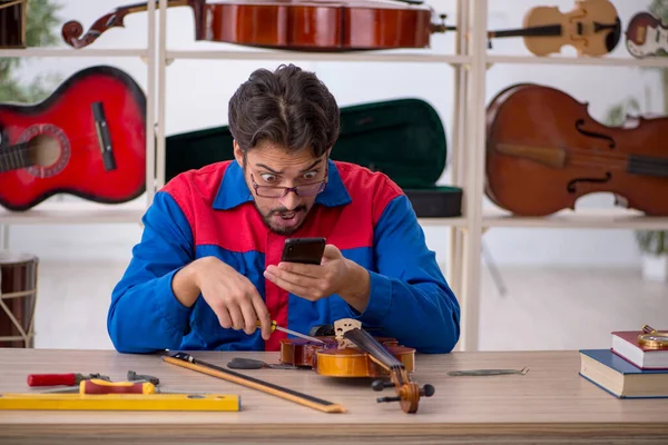 Jovem reparando instrumentos musicais na oficina — Fotografia de Stock