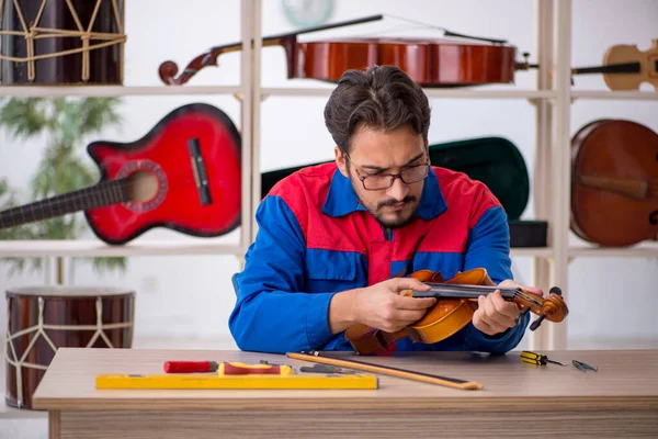 Jongeman repareert muziekinstrumenten in werkplaats — Stockfoto