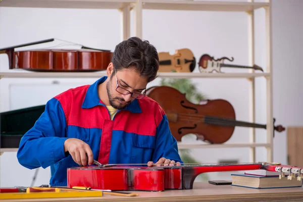 Genç adam atölyede müzik aletlerini tamir ediyor.