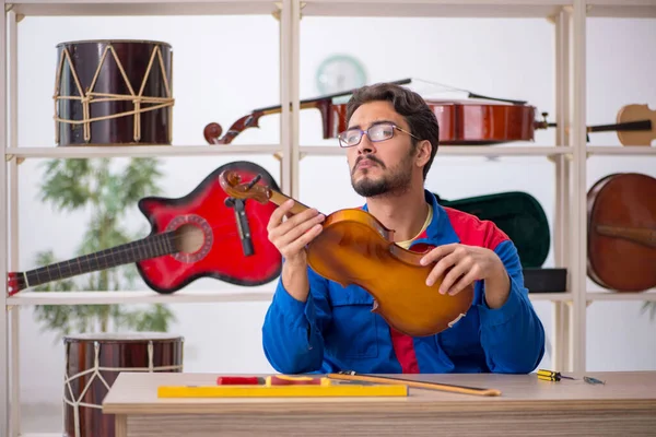 Genç adam atölyede müzik aletlerini tamir ediyor.