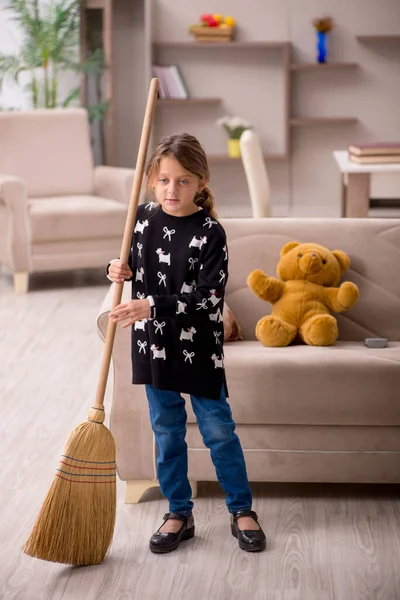 Küçük kız evde ev işi yapıyor.