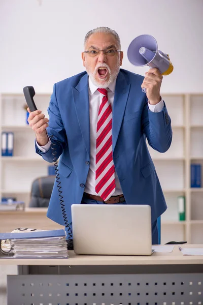 Vecchio uomo d'affari arrabbiato che tiene il megafono in ufficio — Foto Stock