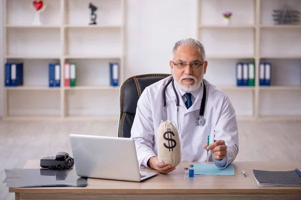 Gammal manlig läkare i lönekoncept — Stockfoto