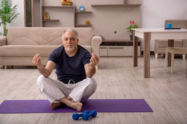 Yaşlı adam evde spor yapıyor.