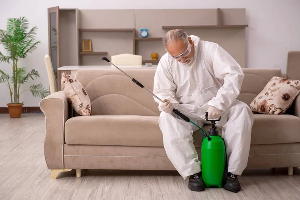 Yaşlı erkek müteahhit evde haşere kontrolü yapıyor.