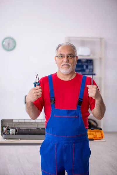 Starý opravář opravující klimatizaci v dílně — Stock fotografie