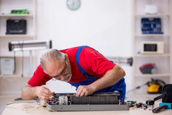 Oude reparateur repareert airconditioner in werkplaats — Stockfoto