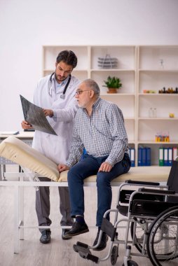 Yaşlı adam genç erkek doktor radyolojisti ziyaret ediyor.