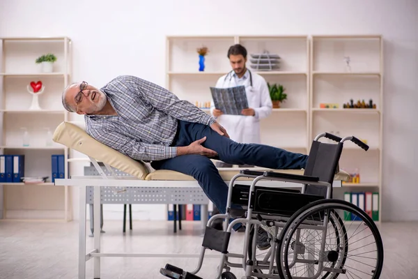 Yaşlı adam genç erkek doktor radyolojisti ziyaret ediyor.