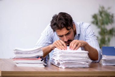 Genç bir erkek çalışan ve ofiste çok fazla iş var.