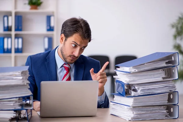 Ung manlig anställd och för mycket arbete på kontoret — Stockfoto