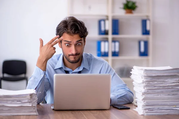 Joven empleado masculino y demasiado trabajo en la oficina —  Fotos de Stock