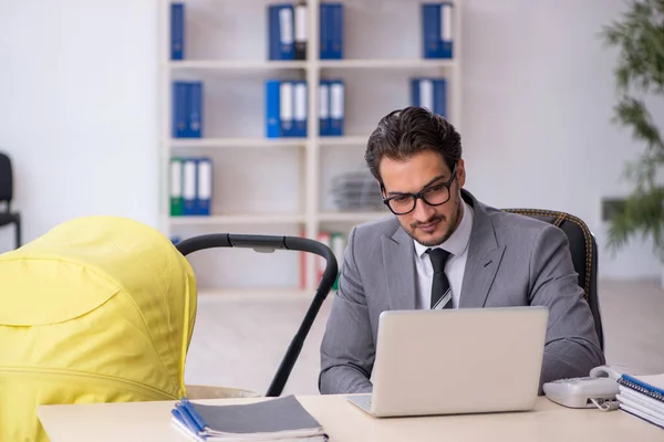 Young male employee looking after new born at workplace — Stock Photo, Image