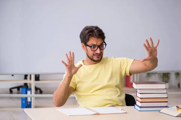 Ung manlig student förbereder sig för tentor i klassrummet — Stockfoto