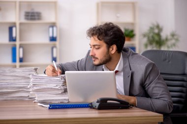 Ofisteki aşırı işten memnun olmayan genç bir erkek işçi.