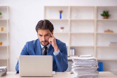 Genç bir erkek çalışan ve ofiste çok fazla iş var.