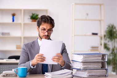 Genç bir erkek çalışan ve ofiste çok fazla iş var.