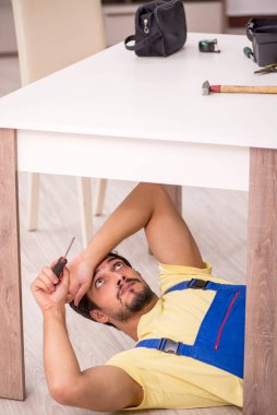 Genç erkek marangoz evdeki masayı onarıyor.