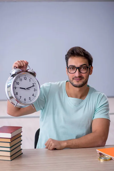 Joven estudiante masculino en concepto de gestión del tiempo en el aula — Foto de Stock