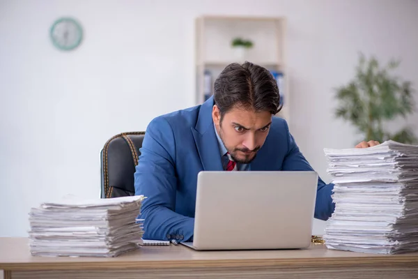 Joven empleado masculino y demasiado trabajo en la oficina — Foto de Stock