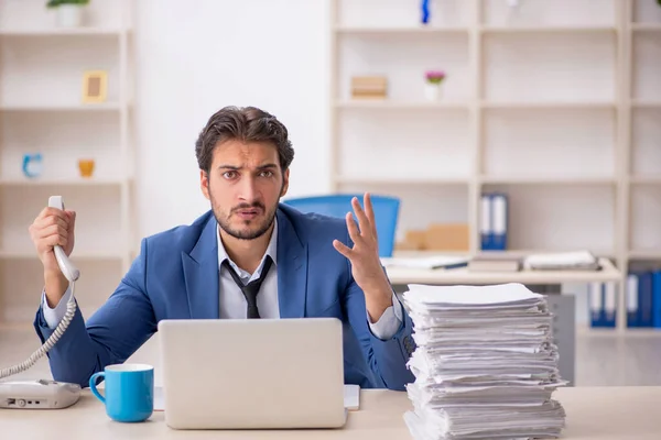 Joven empleado masculino y demasiado trabajo en la oficina —  Fotos de Stock