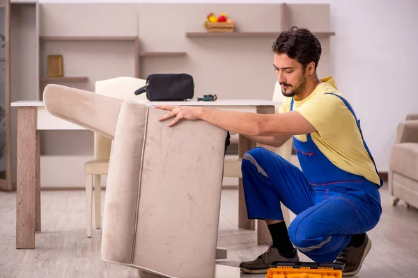 Genç erkek marangoz evde koltuk tamir ediyor. — Stok fotoğraf