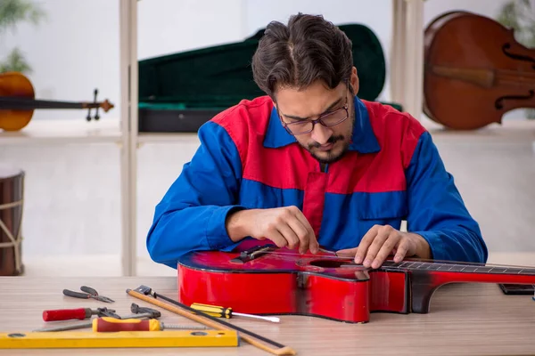 Молодой человек ремонтирует музыкальные инструменты в мастерской — стоковое фото