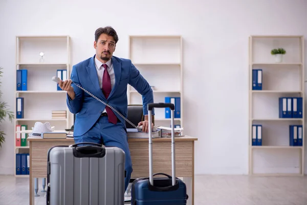 Young male employee preparing for trip at workplace — Stock Photo, Image