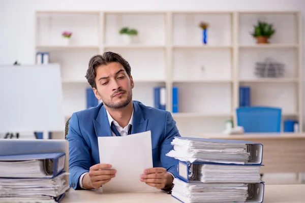 Joven empleado masculino y demasiado trabajo en la oficina — Foto de Stock