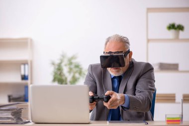 Eski erkek çalışanın iş yerinde sanal gözlüklerin keyfini çıkarması