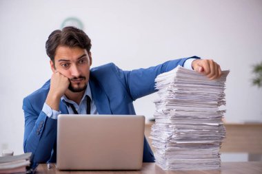 Ofisteki aşırı işten memnun olmayan genç bir erkek işçi.