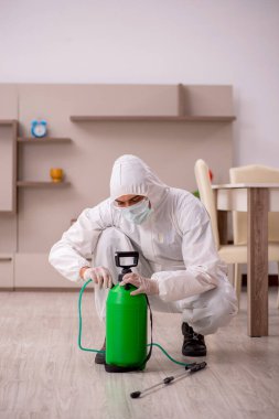 Genç erkek müteahhit evde haşere kontrolü yapıyor.