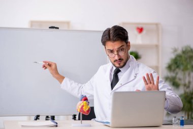 Sınıfta oturan genç erkek kardiyolog.