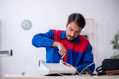 Genç erkek tamirci ısıtıcıyı tamir ediyor.