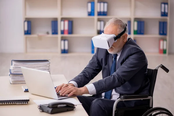 Old leg injured male employee wearing virtual glasses at workpla