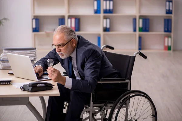 Старый работник в инвалидной коляске в счастливой идее — стоковое фото