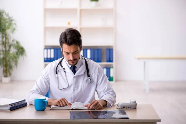 Ung manlig läkare läser bok på kliniken — Stockfoto