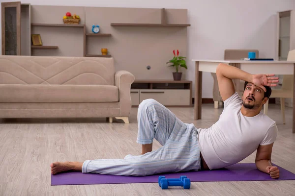 Jovem fazendo exercícios esportivos em casa — Fotografia de Stock