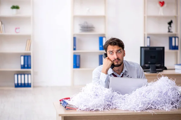 Młody pracownik płci męskiej i dużo papierów ciętych w biurze — Zdjęcie stockowe