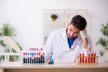Genç erkek biyokimyacı kan örneklerini pandemik konseptte test ediyor.