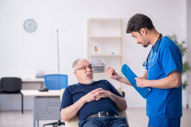 Yaşlı adam genç erkek doktoru ziyaret ediyor.