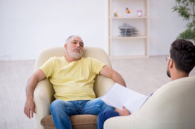 Yaşlı adam genç erkek psikoterapisti ziyaret ediyor.