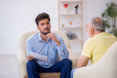 Yaşlı adam genç erkek psikoterapisti ziyaret ediyor.