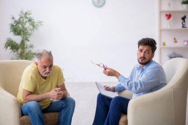 Yaşlı adam genç erkek psikoterapisti ziyaret ediyor.