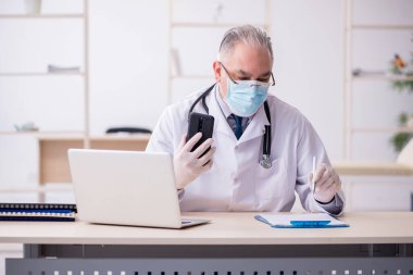 Klinikte çalışan yaşlı erkek doktor.