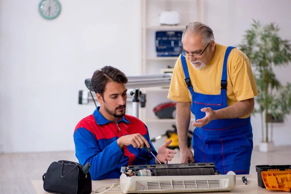 Två manliga reparatörer som reparerar luftkonditioneringen — Stockfoto